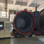 Industrial horizontal vacuum annealing furnace with open door and digital control panel in a factory setting.